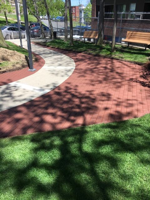 A park with a brick walkway and a bench