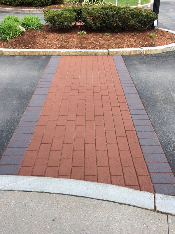 A red and black brick walkway leading to a parking lot