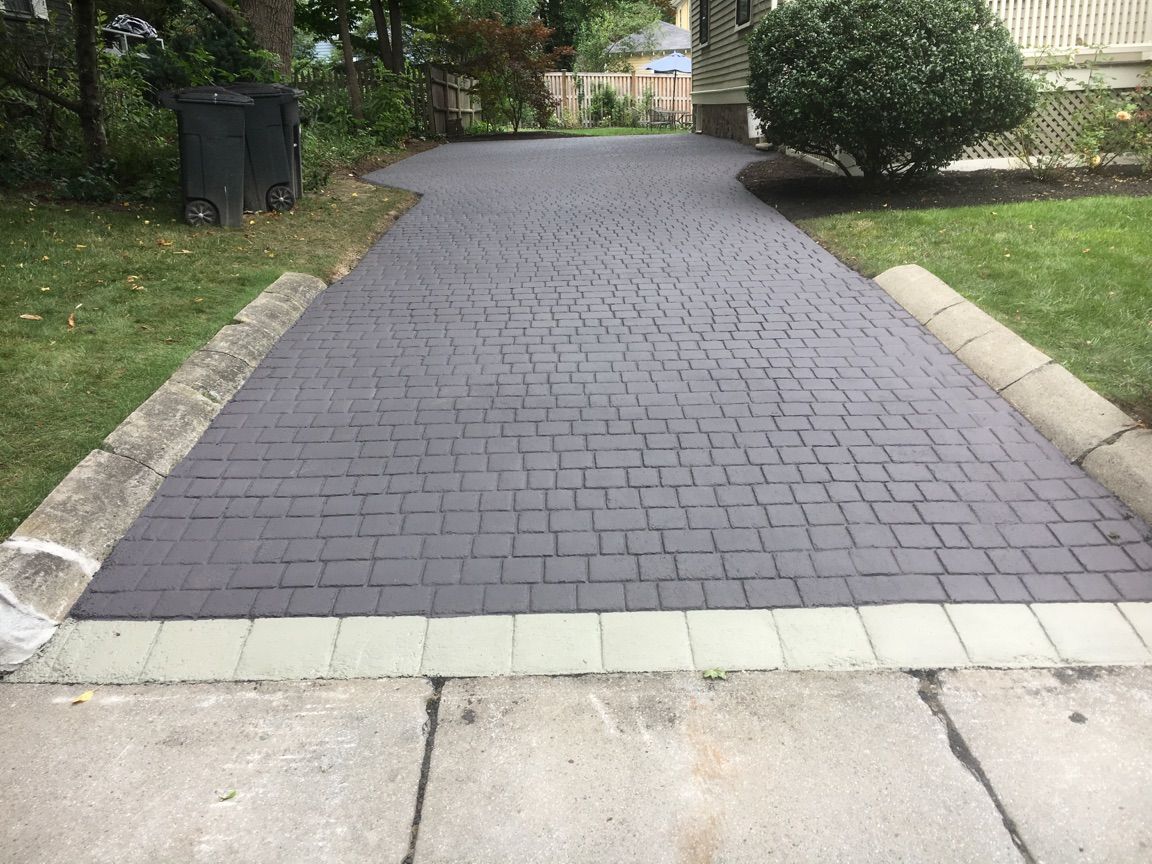 A brick driveway leading to a house with a white curb.