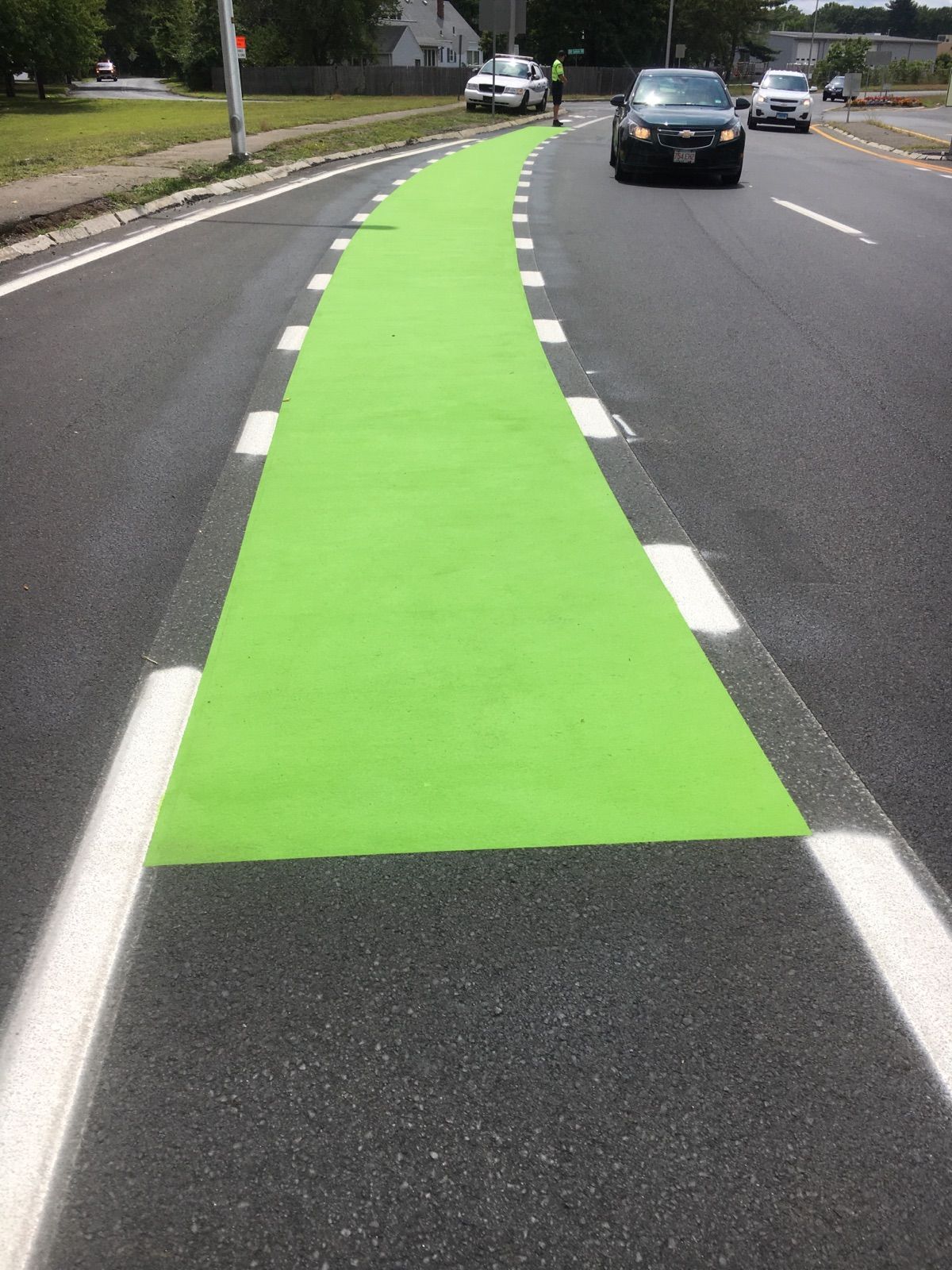 A car is driving down a road with a green line painted on it.
