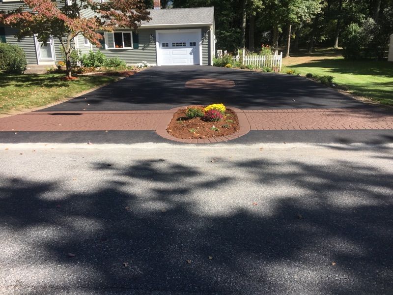 A driveway leading to a house with flowers in the middle