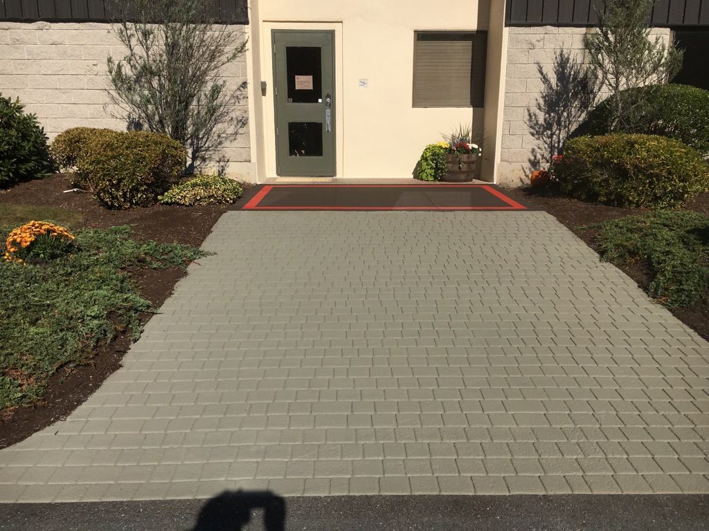A brick walkway leads to a building with a green door