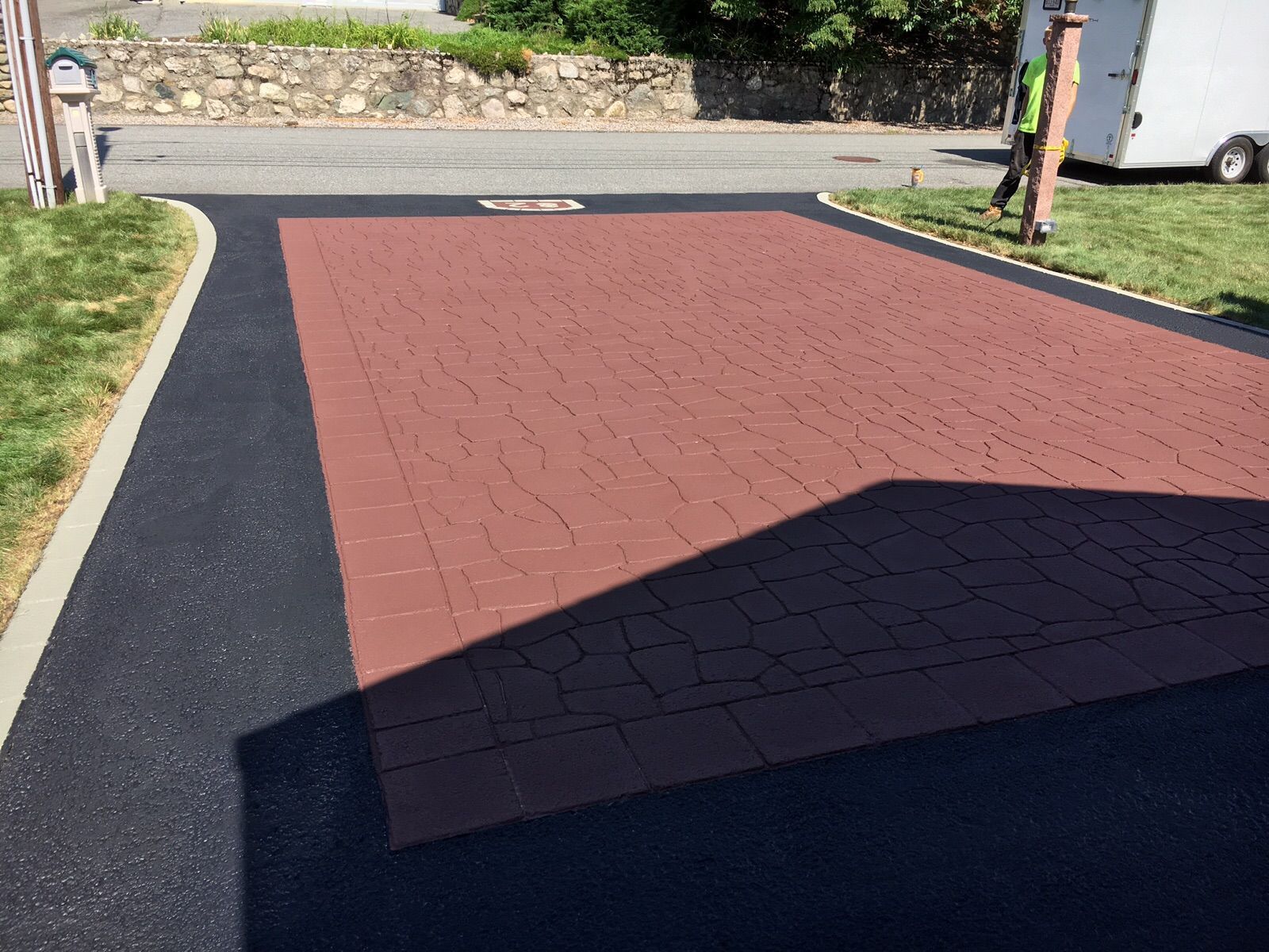 A black and red brick driveway with a shadow on the ground