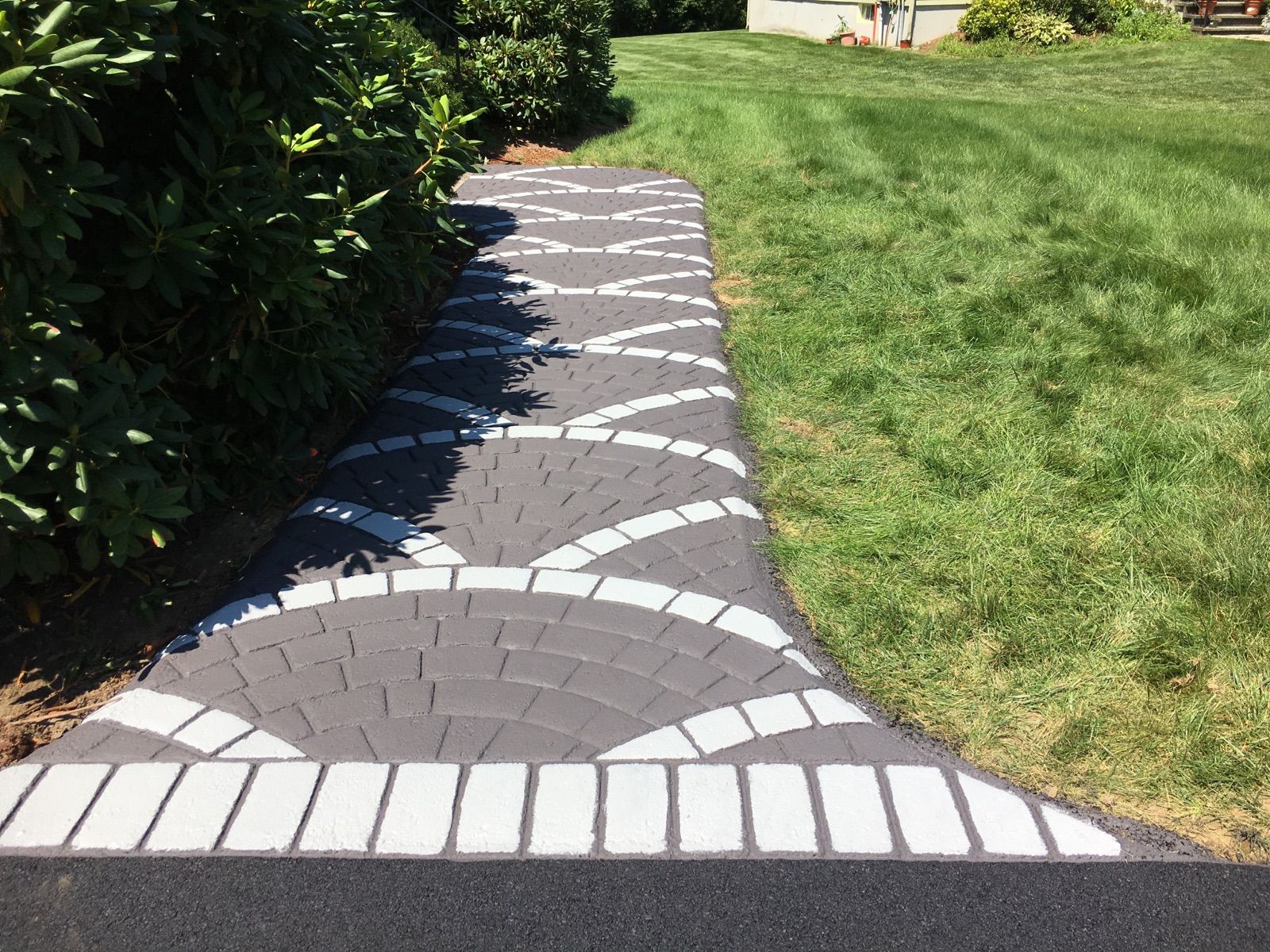 A black and white walkway leading to a lush green lawn.