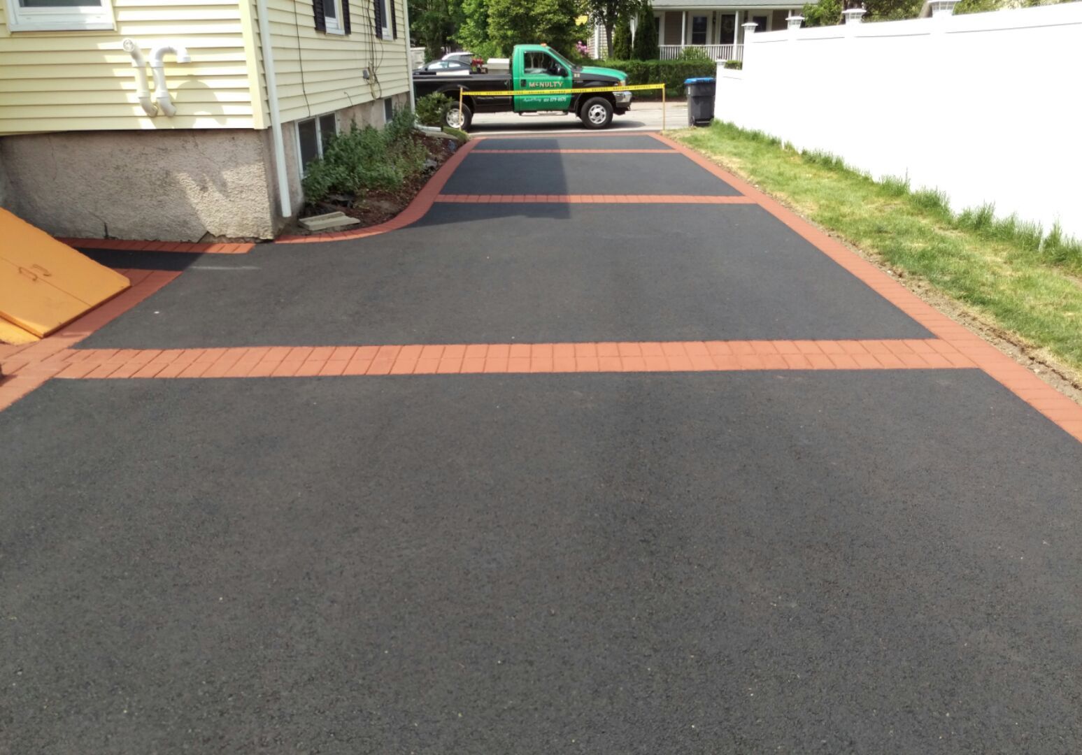 A green truck is parked in a driveway next to a house