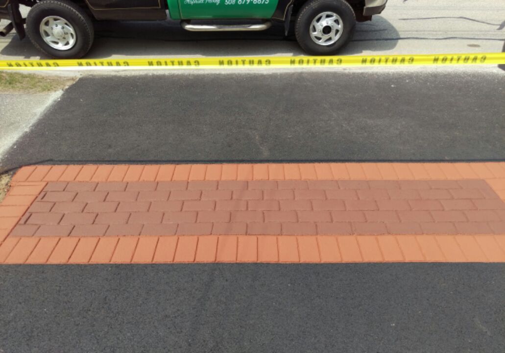 A green truck is parked next to a brick walkway