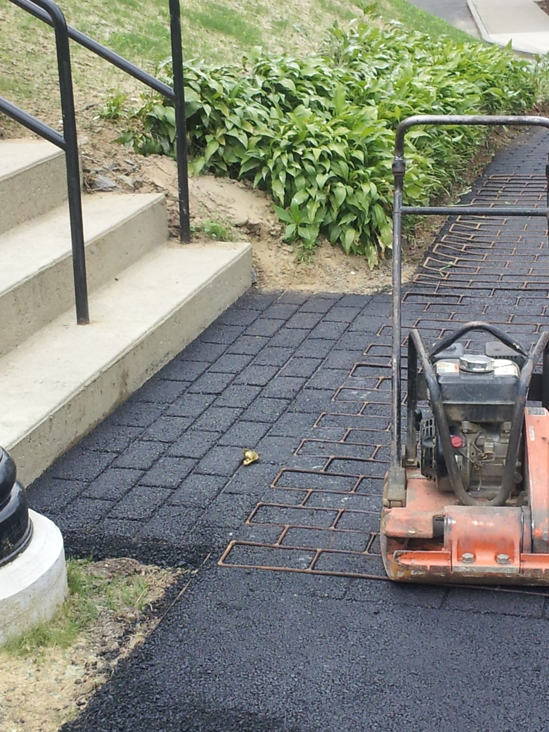 A machine is sitting on a sidewalk next to stairs.