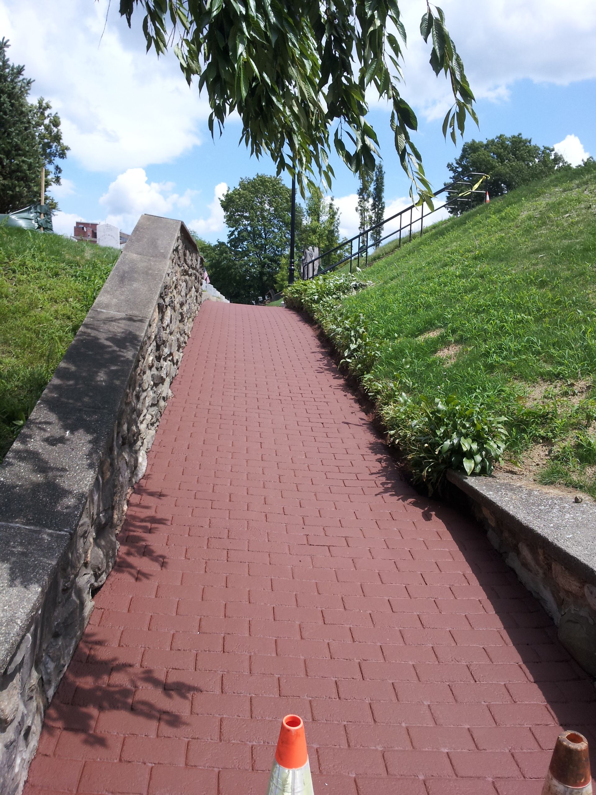 A brick walkway leading up to a grassy hillside