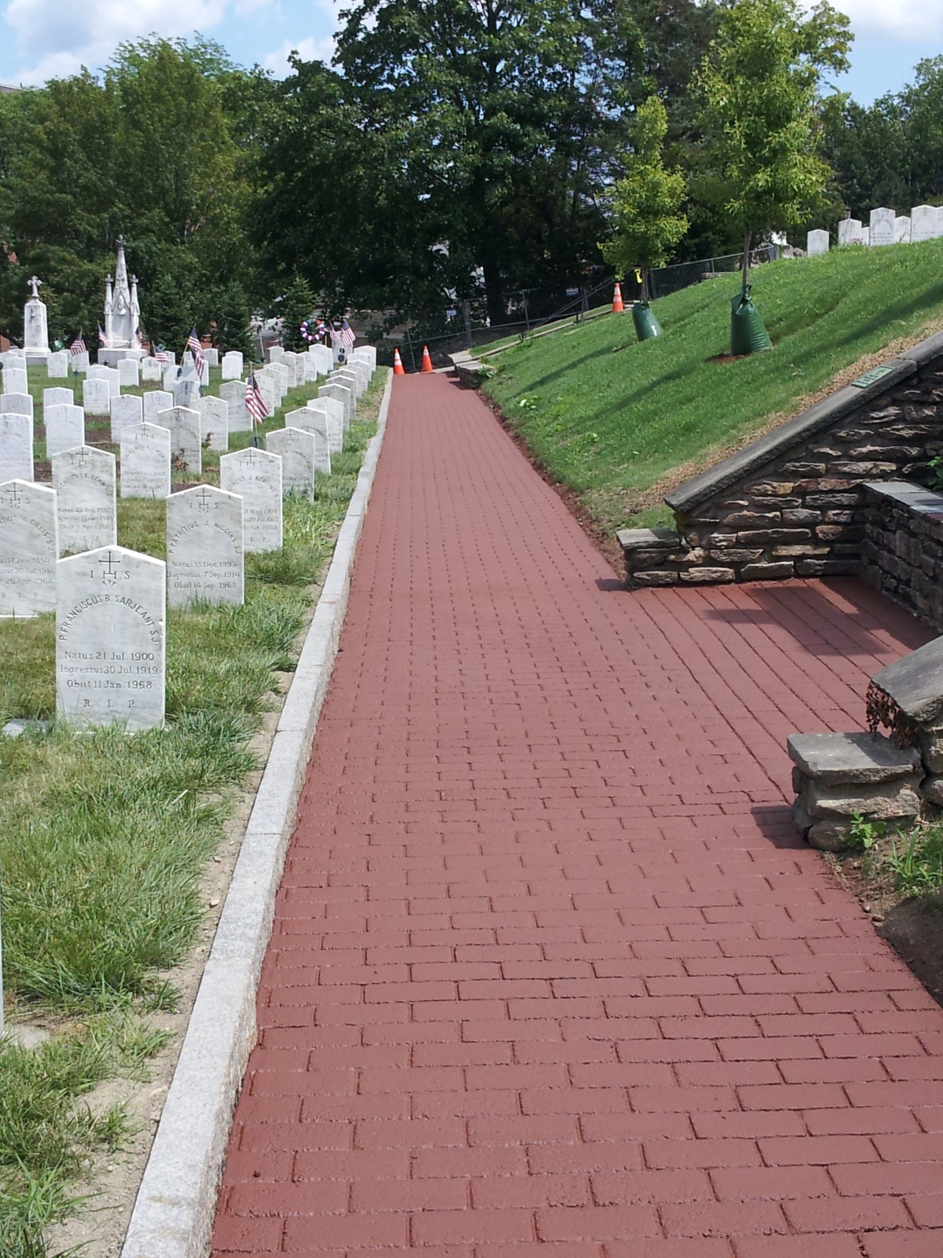 A red brick walkway going through a cemetery