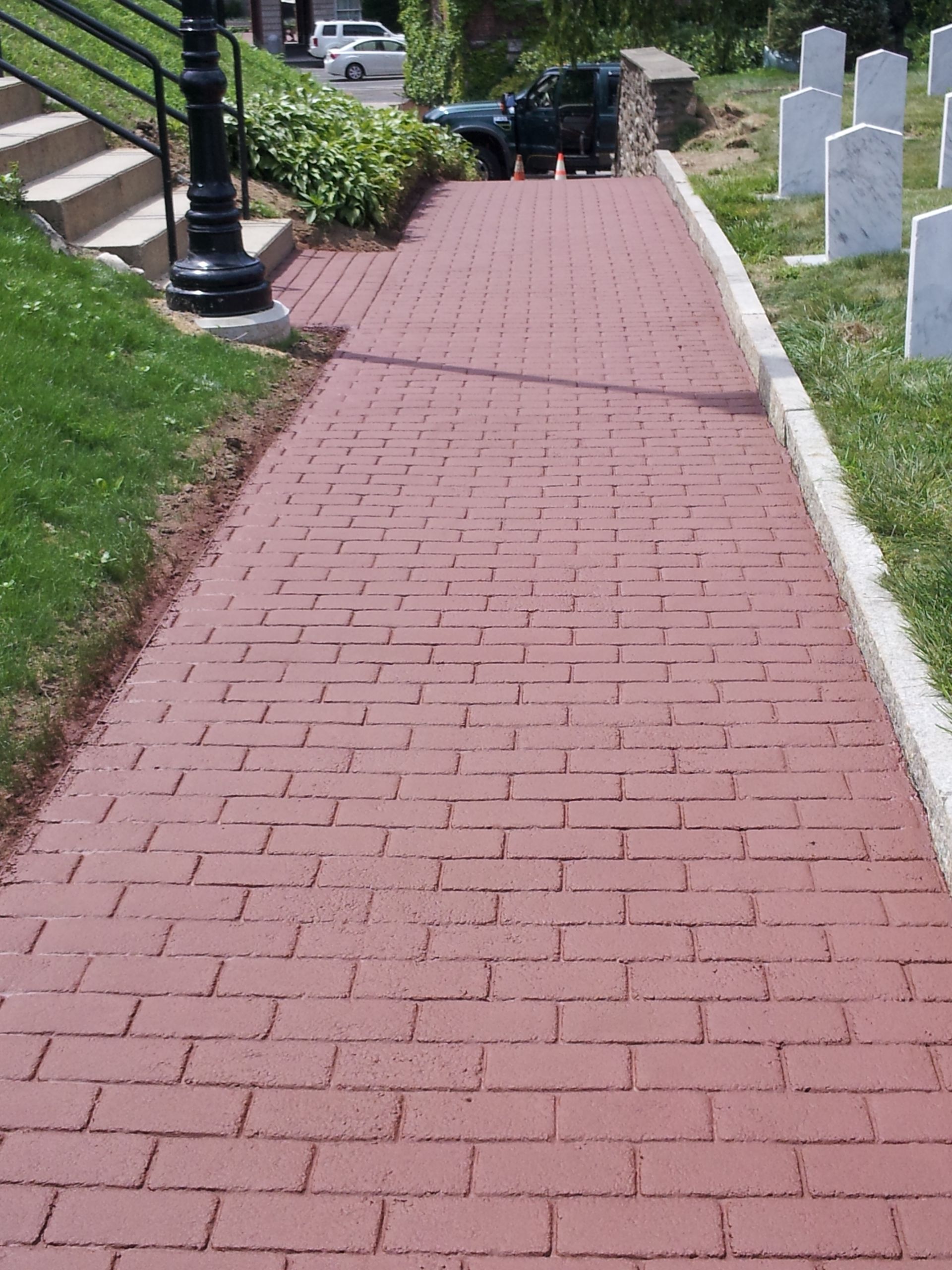 A red brick walkway leading to a cemetery