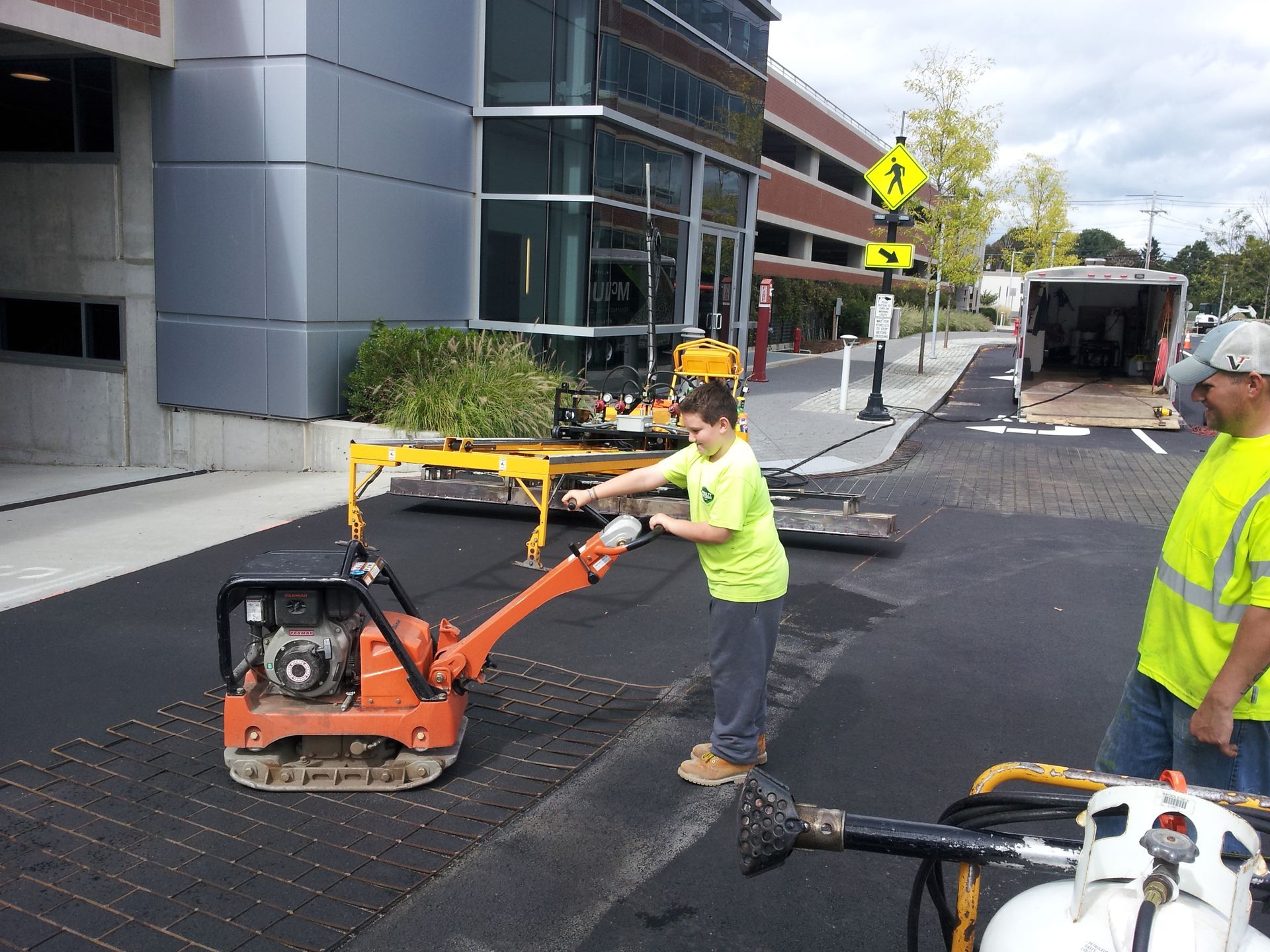 A man in a green shirt is pushing a machine on a road