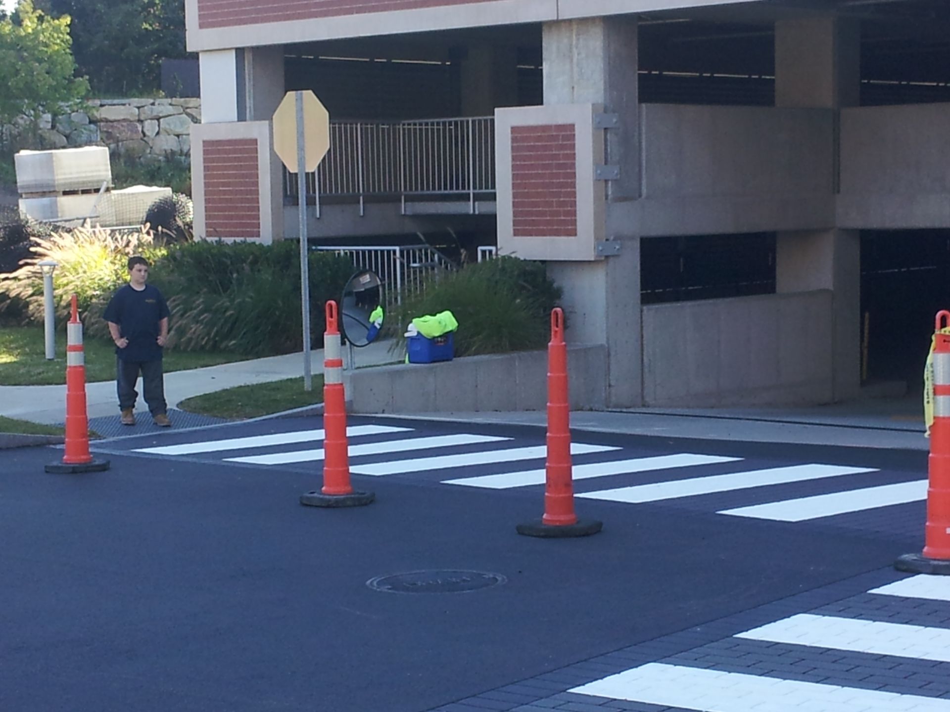 A man walks across a crosswalk in front of a parking garage