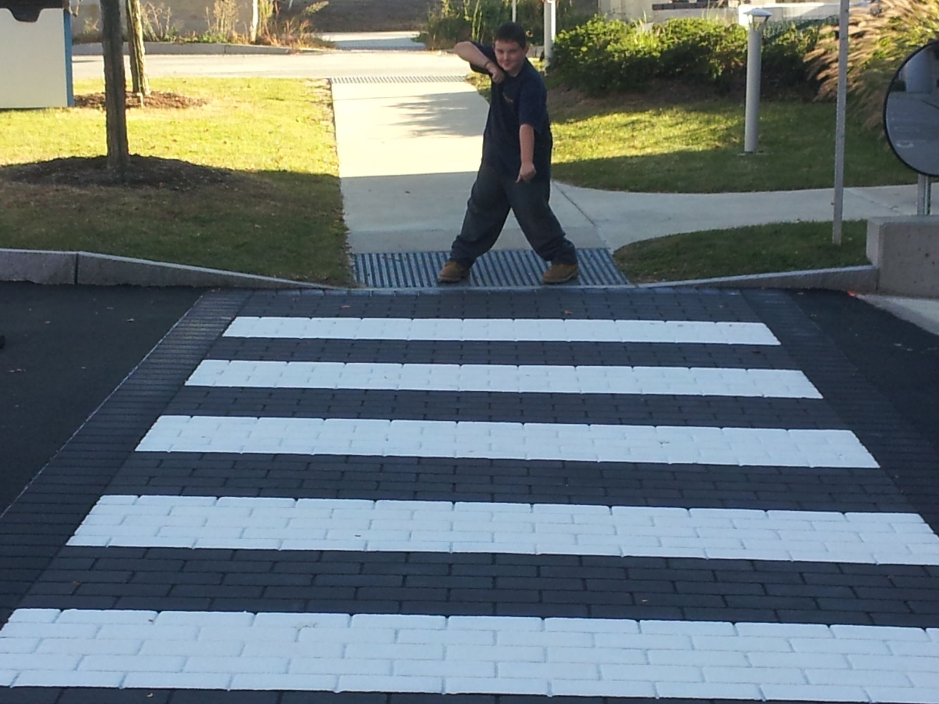 A man is crossing a black and white brick crosswalk