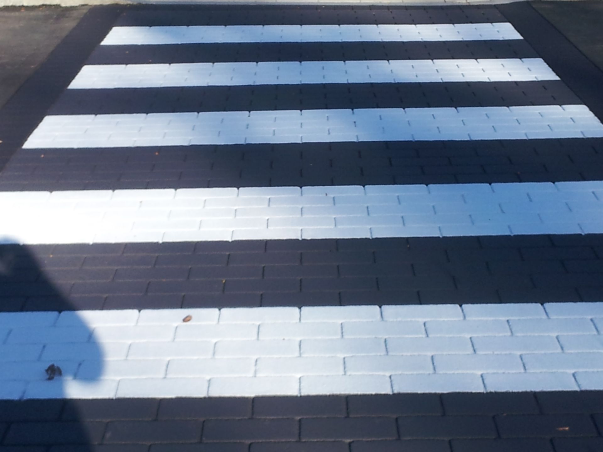 A black and white brick crosswalk with white stripes