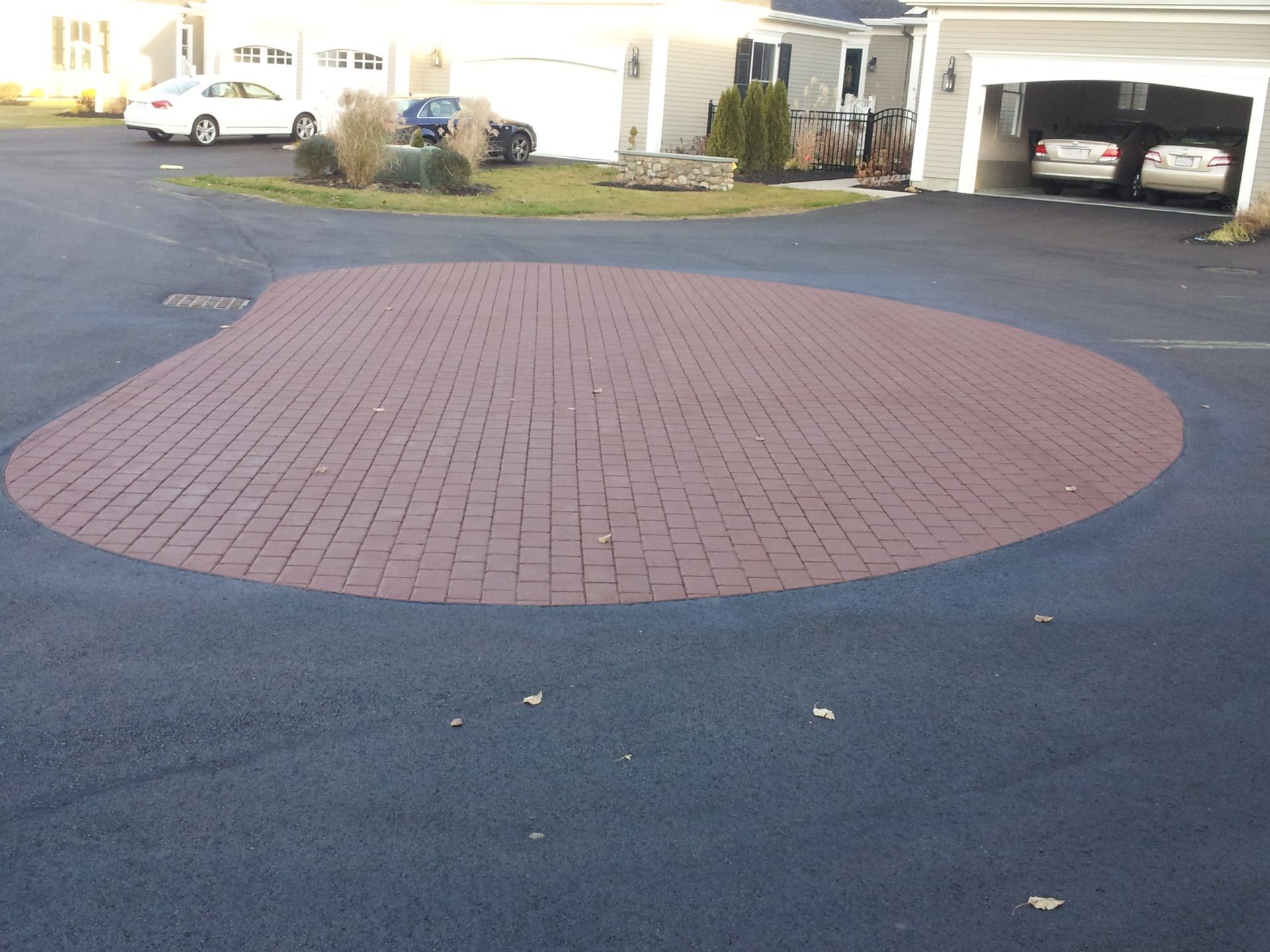 A driveway with a brick circle in the middle of it