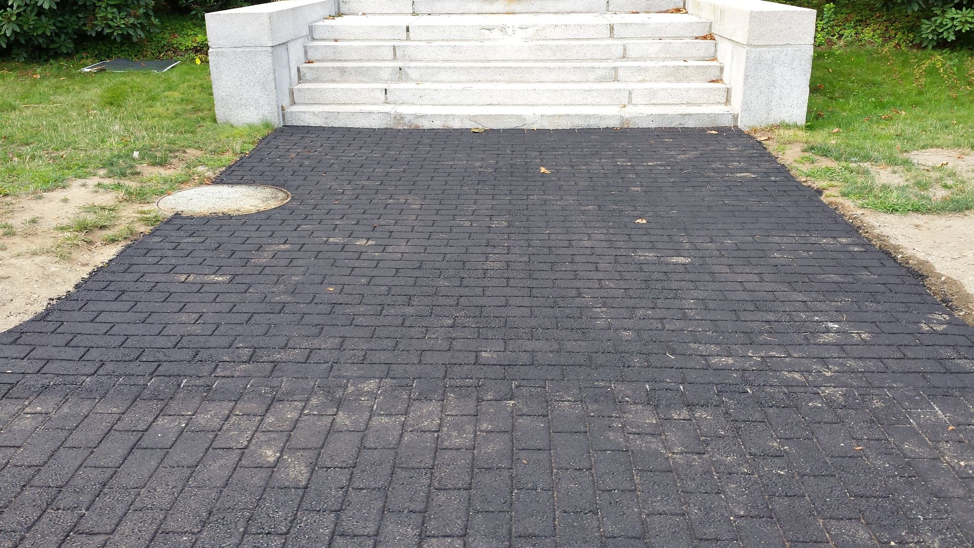 A black brick walkway leading to a set of stairs.