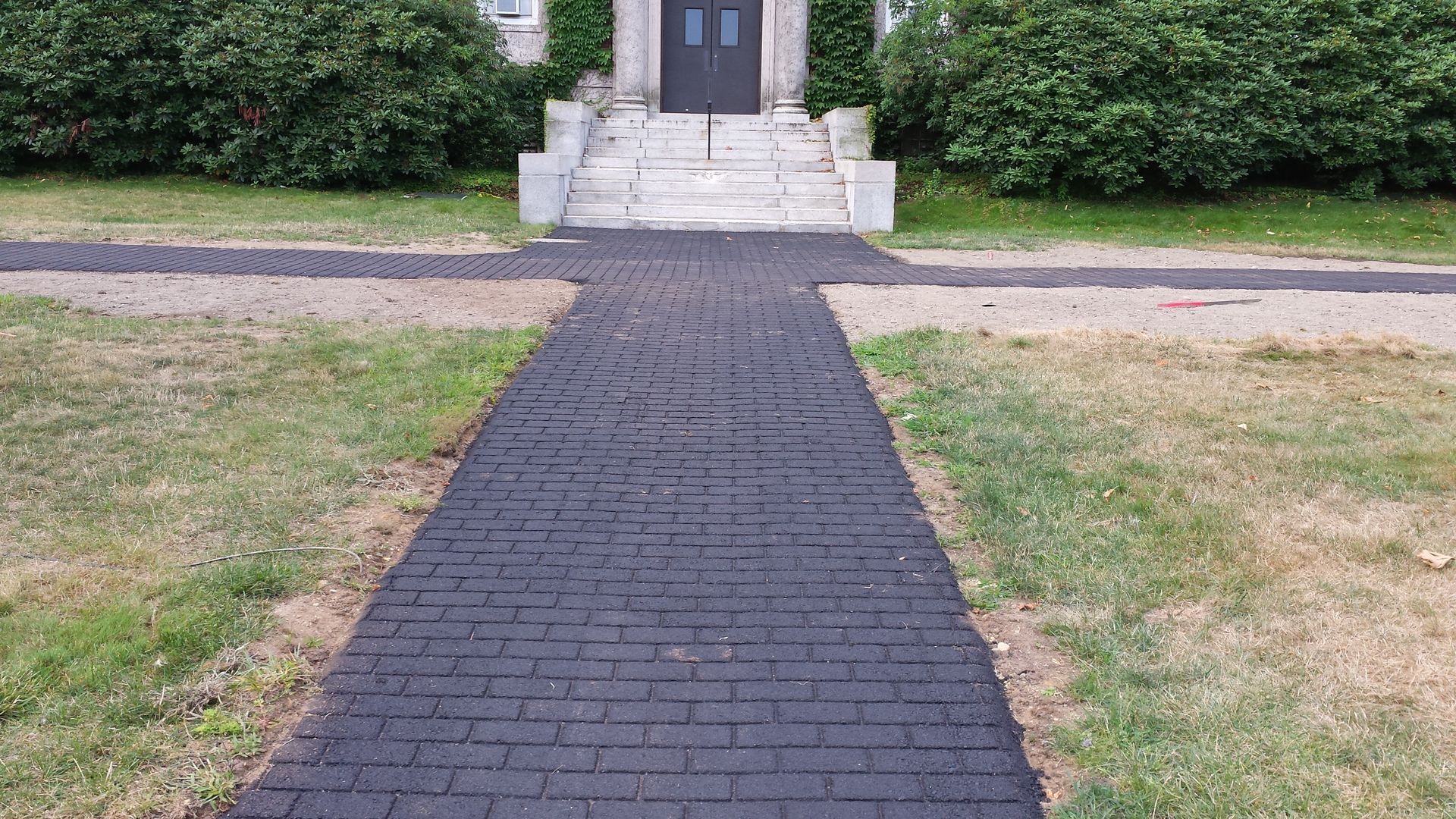 A black brick walkway leading to a building with stairs.