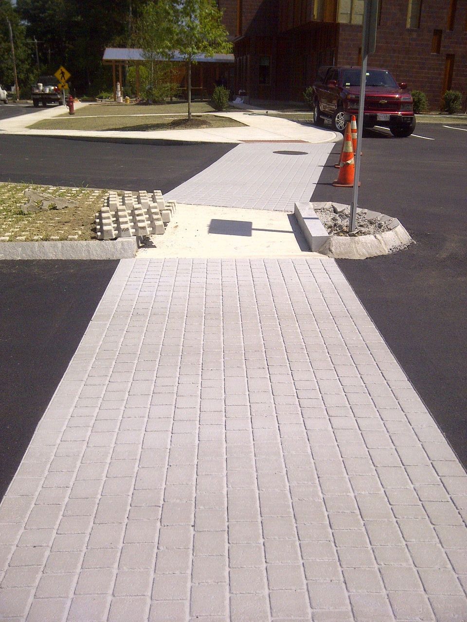 A red truck is parked in a parking lot next to a brick walkway