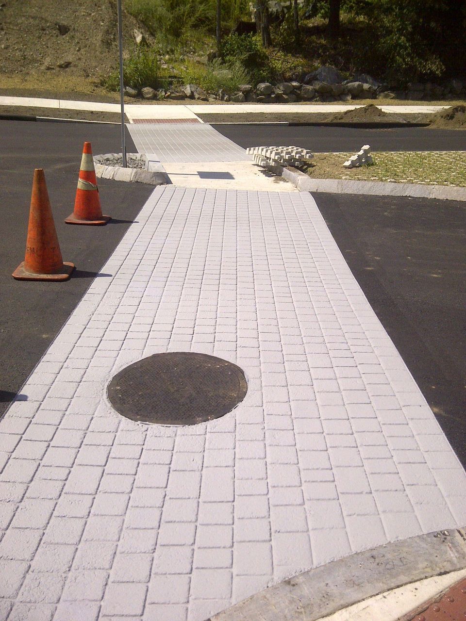 A brick walkway with a manhole cover in the middle