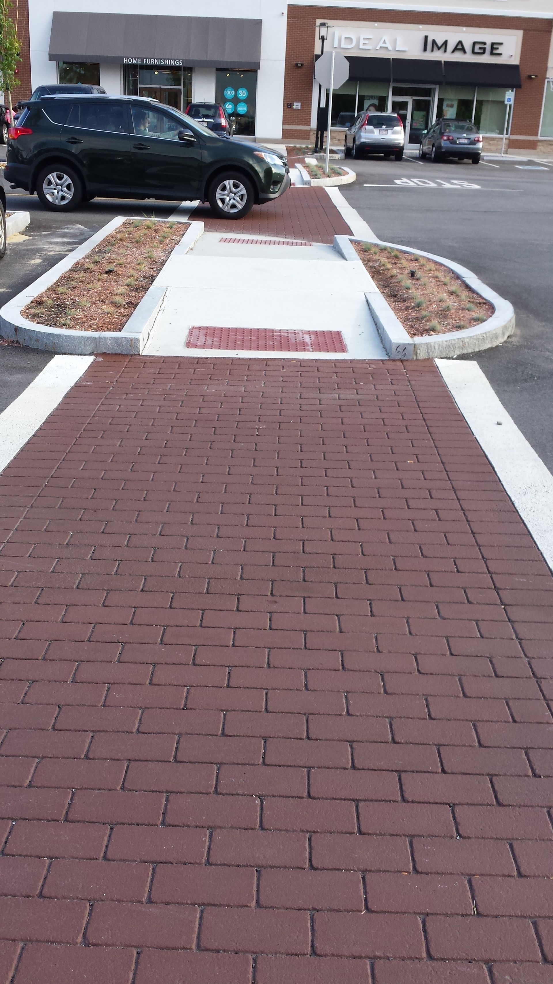 A black suv is parked in a parking lot next to a brick walkway.