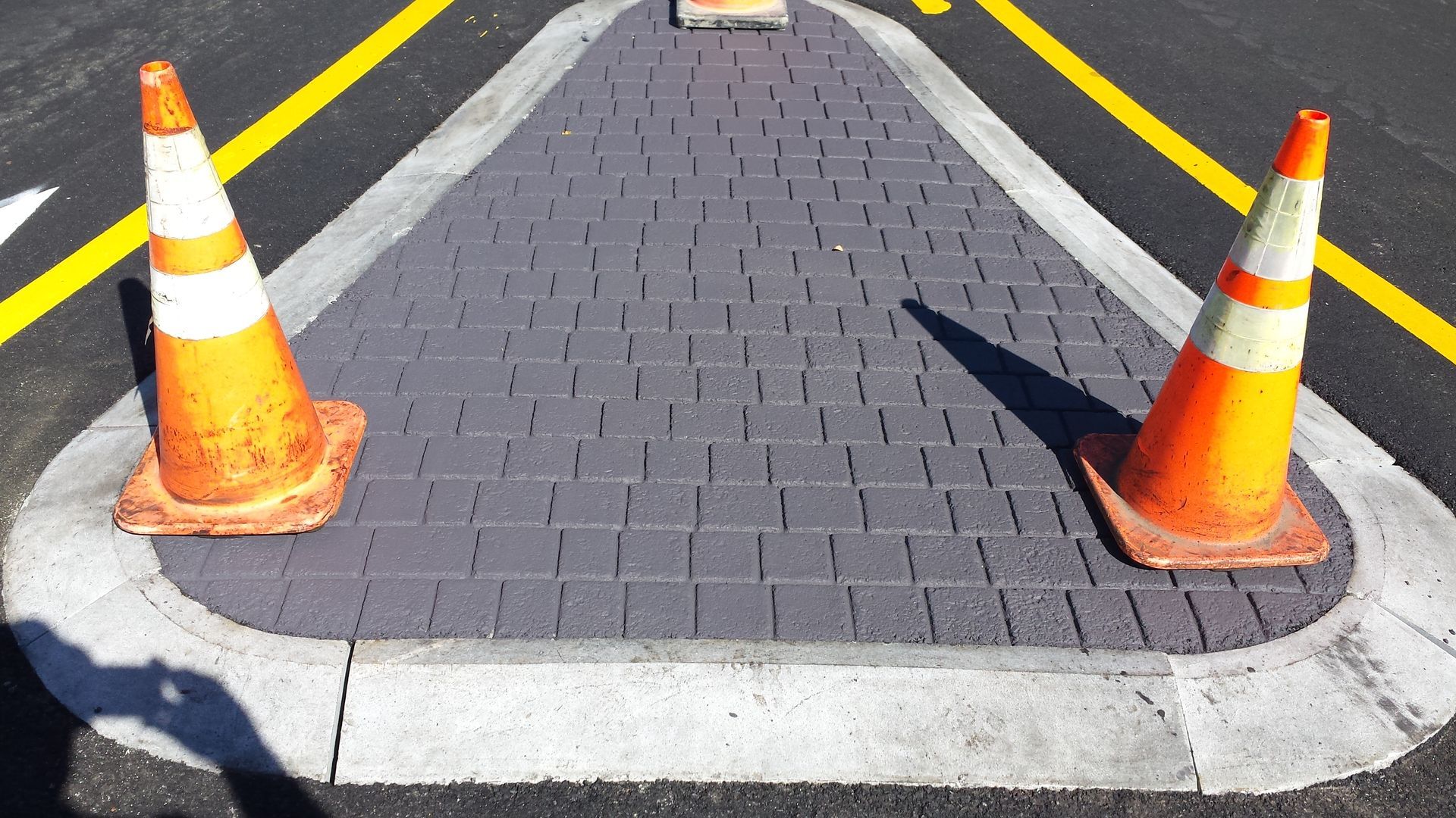 Two orange and white traffic cones are on the side of the road