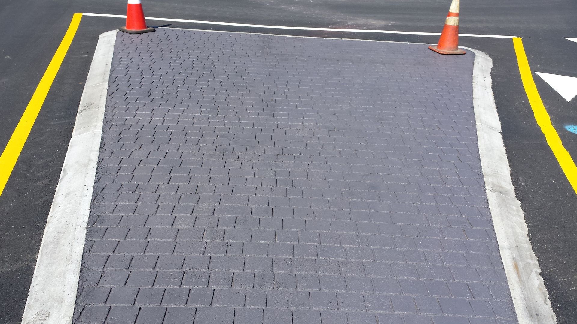 A brick walkway with two orange cones on the side of it