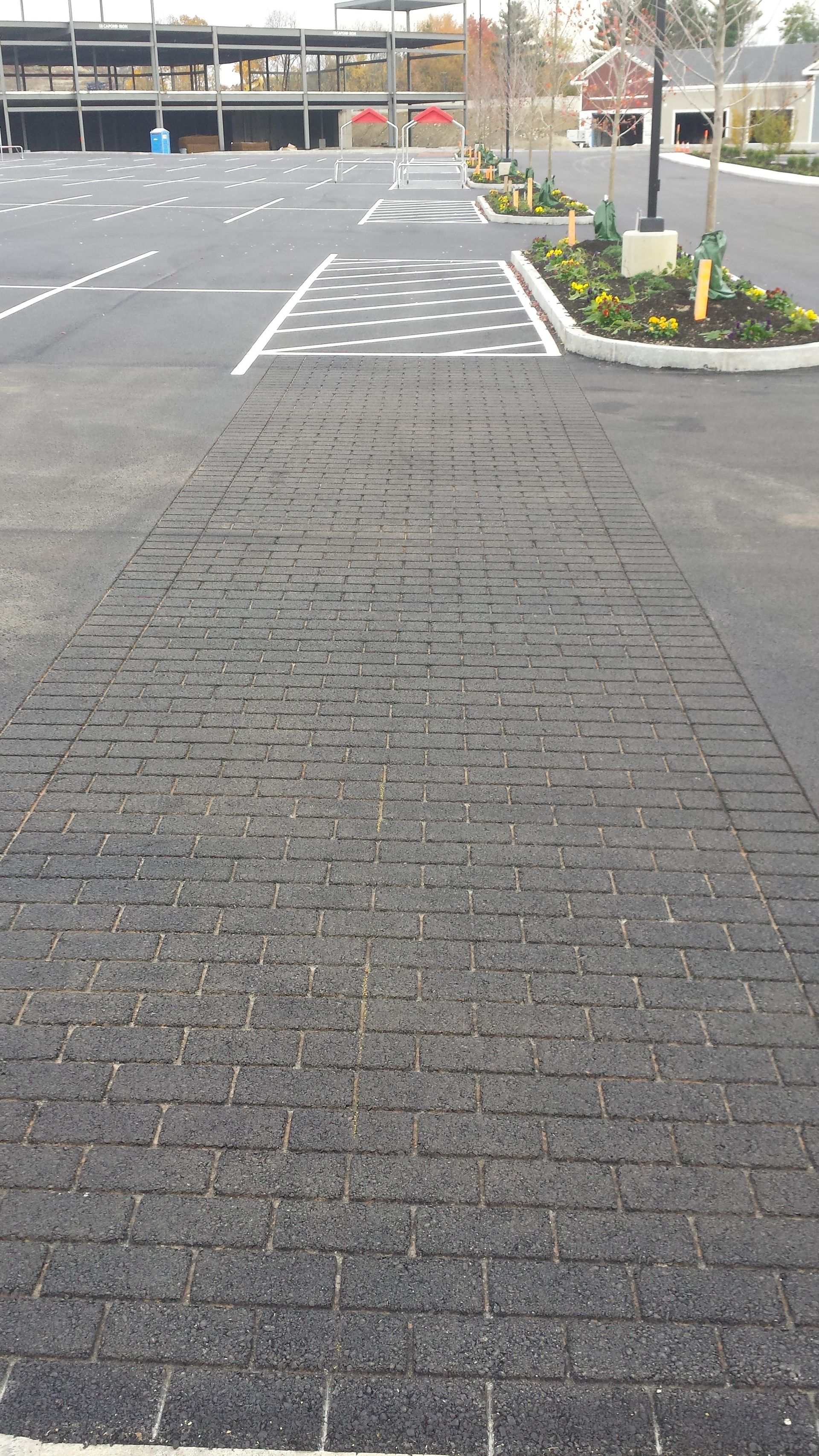 A parking lot with a brick walkway leading to it.
