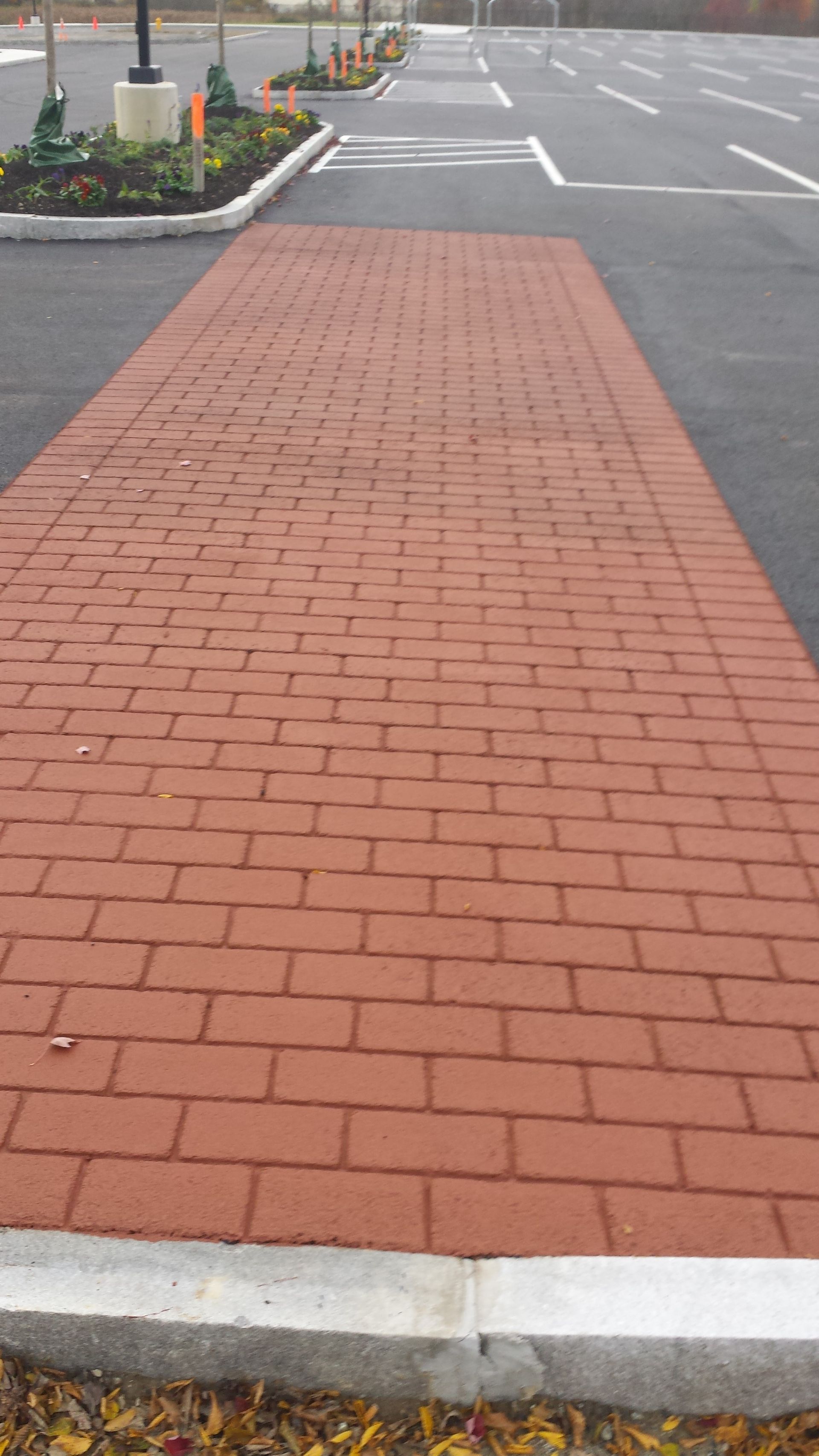 A red brick walkway leading to a parking lot.