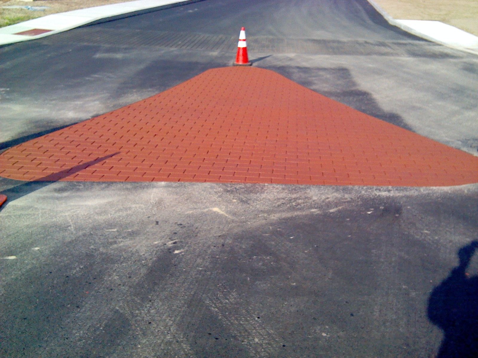 A red and white traffic cone is on the side of a road