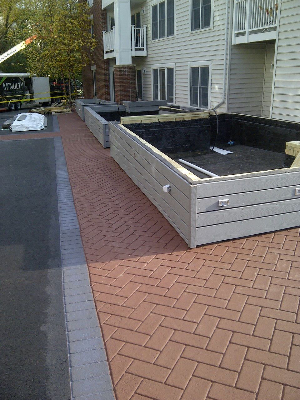 A brick walkway with a white fence in front of a building