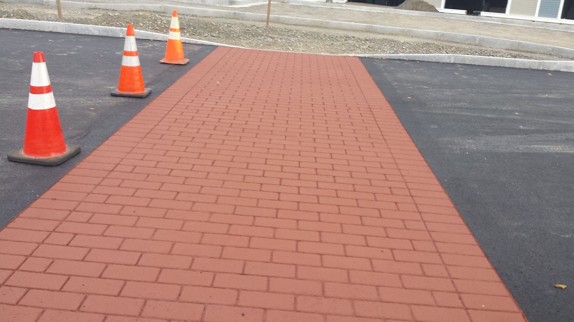 A row of orange and white traffic cones on a brick walkway