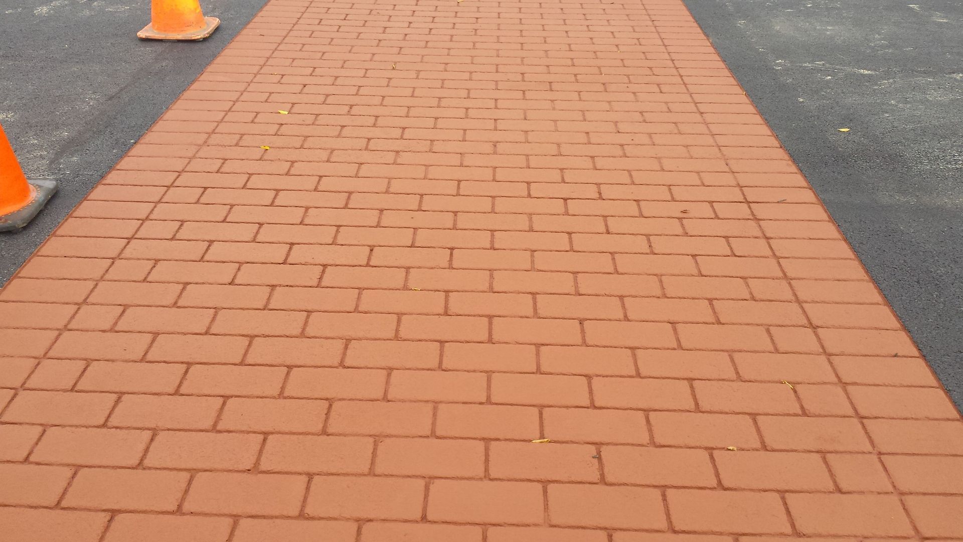 A brick walkway with orange traffic cones on the side