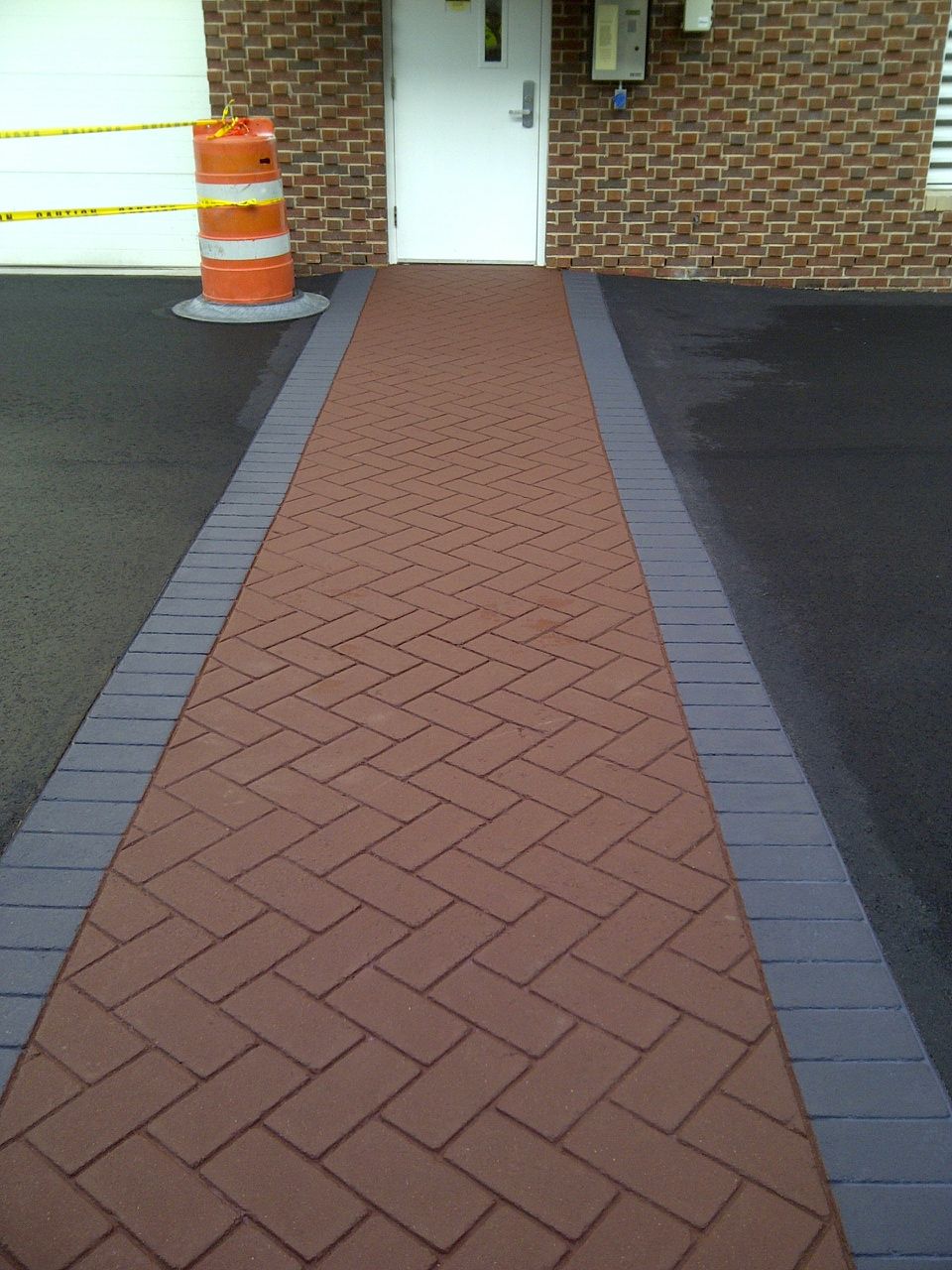 A brick walkway leading to a white door