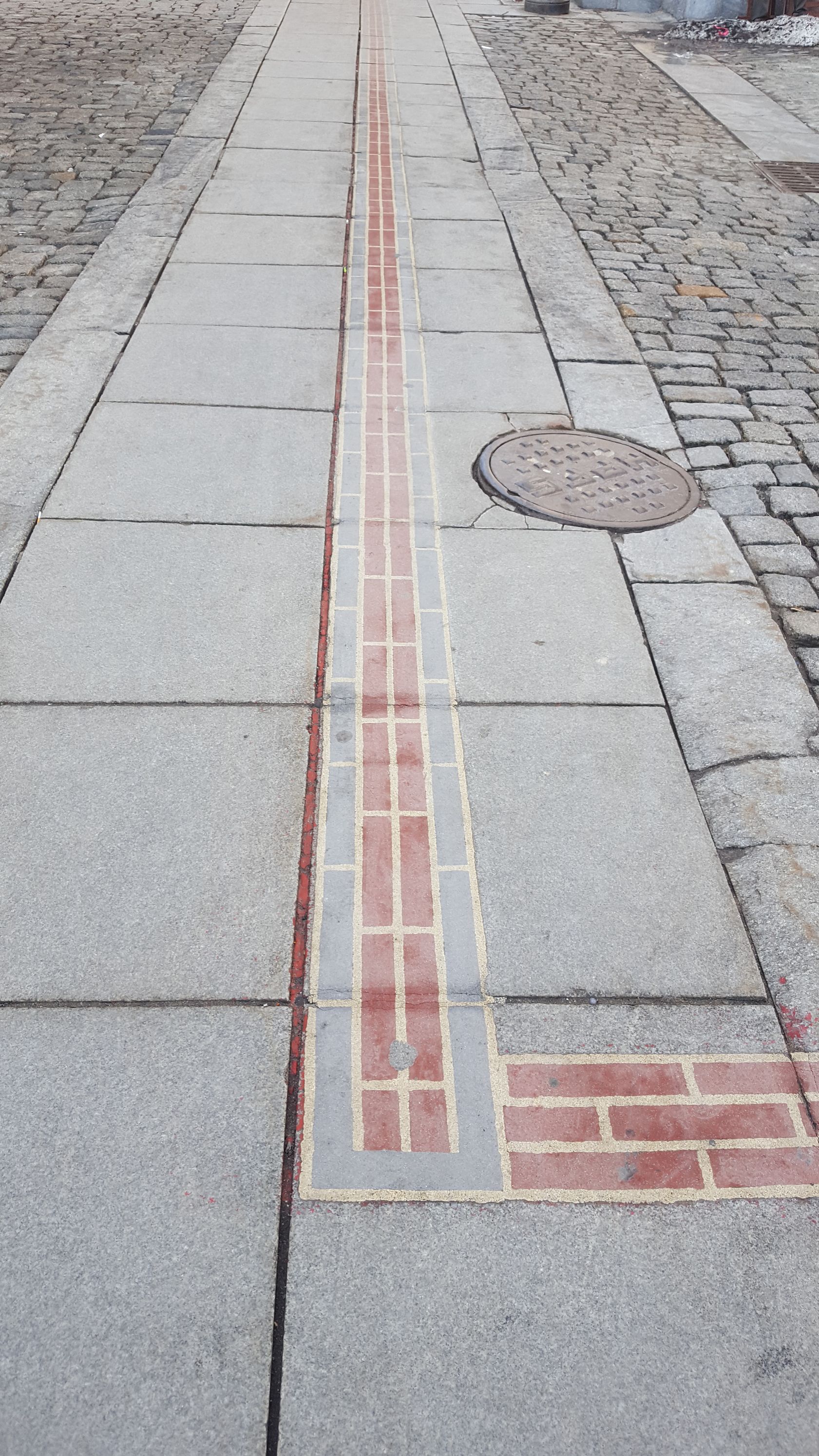 A brick walkway with a red line on it
