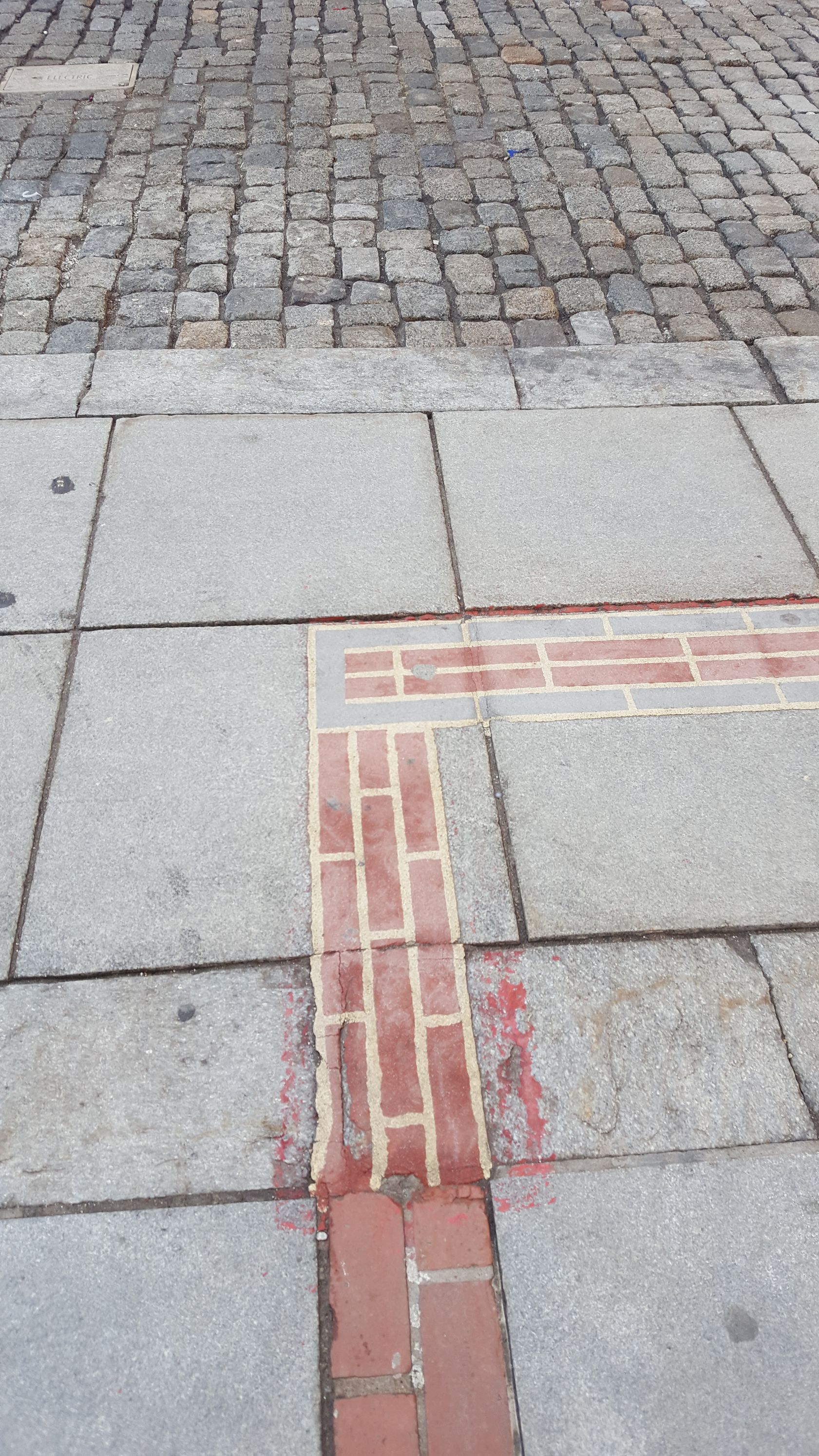 A brick walkway with a red line painted on it