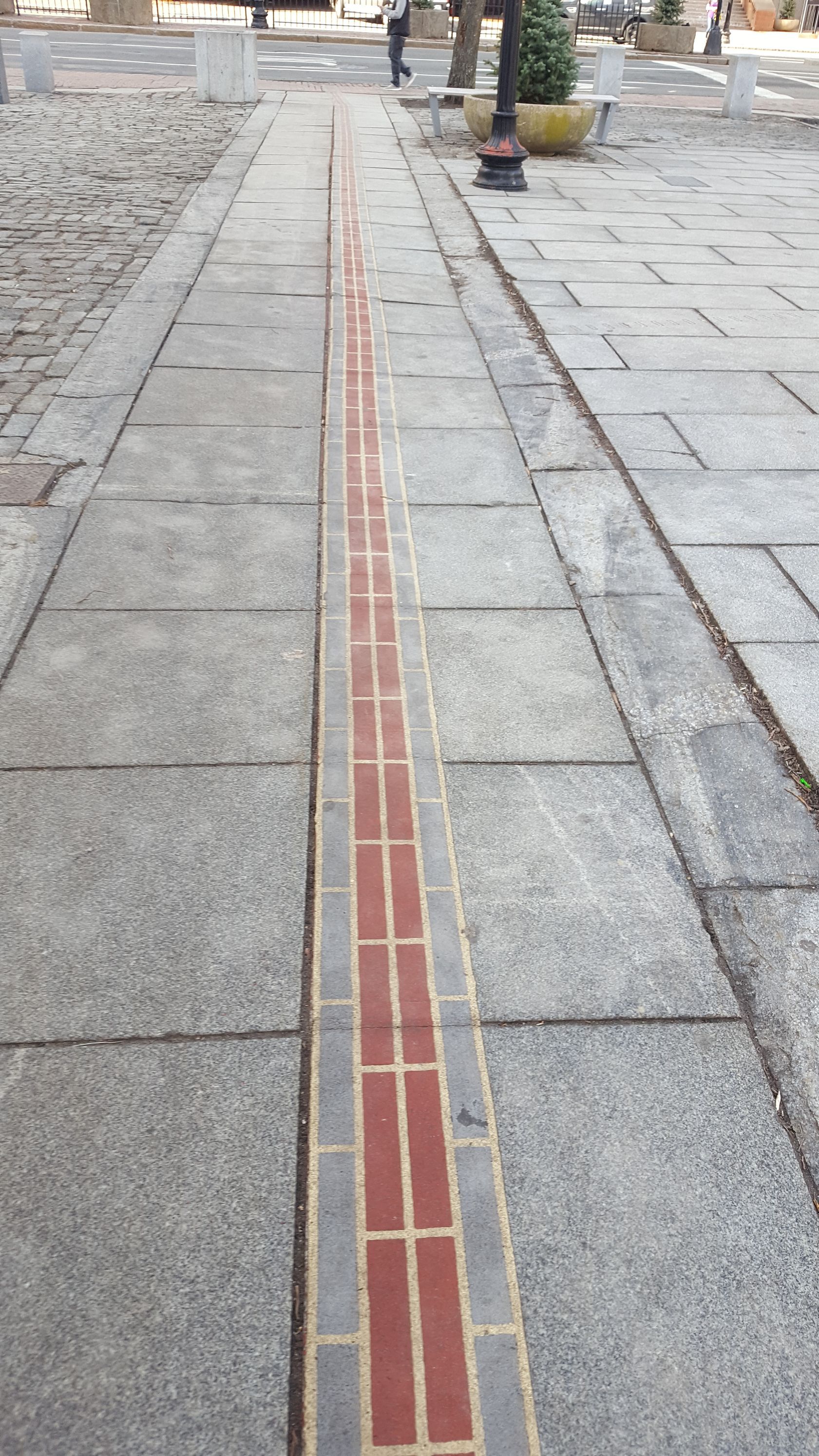 A brick walkway with a red line in the middle