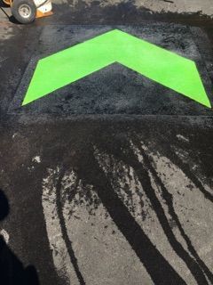 A green arrow is painted on a black surface