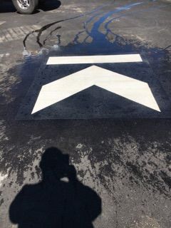 A person is taking a picture of an arrow on the ground.