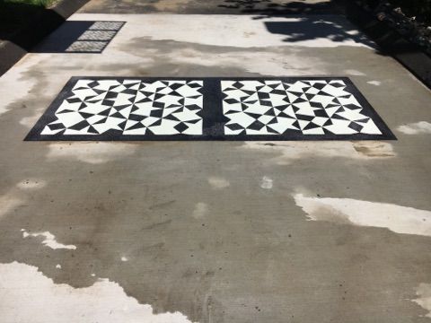 A concrete driveway with a black and white pattern on it