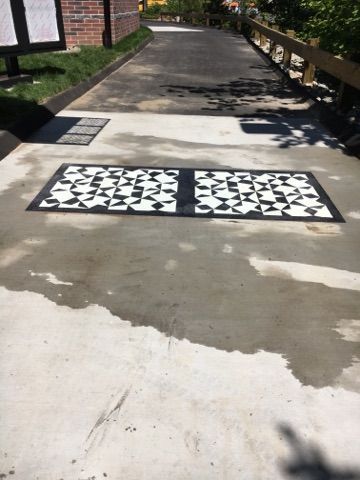 A concrete driveway with a black and white checkered pattern on it.