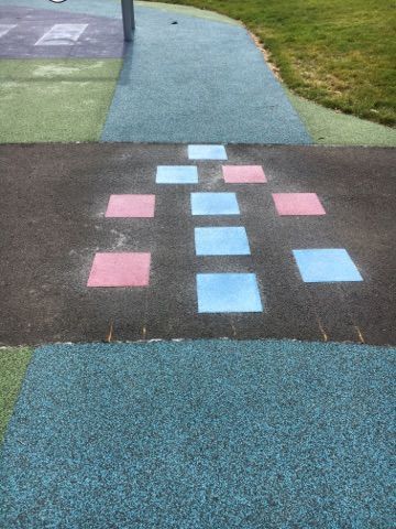 A playground with pink and blue squares painted on the ground.