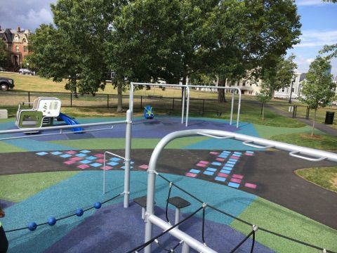 A playground with a ropes course and a swing set.