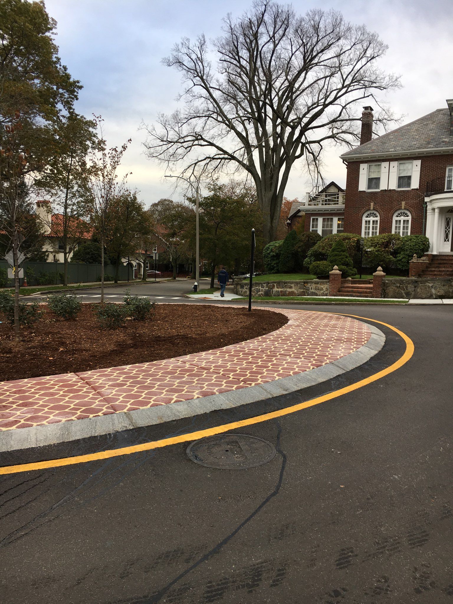 A road with a brick curb and a house in the background