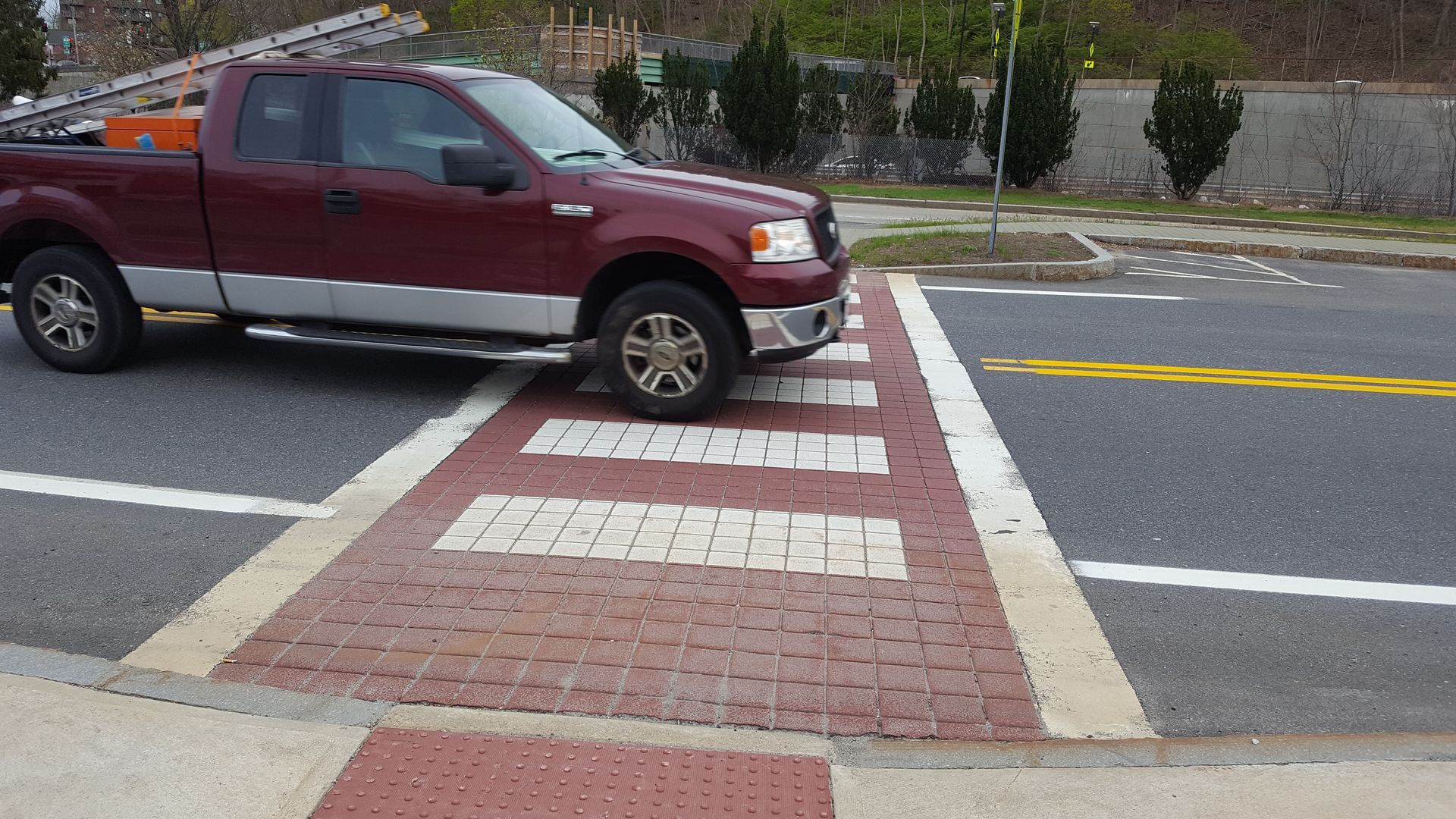A red truck is parked on the side of the road at a crosswalk