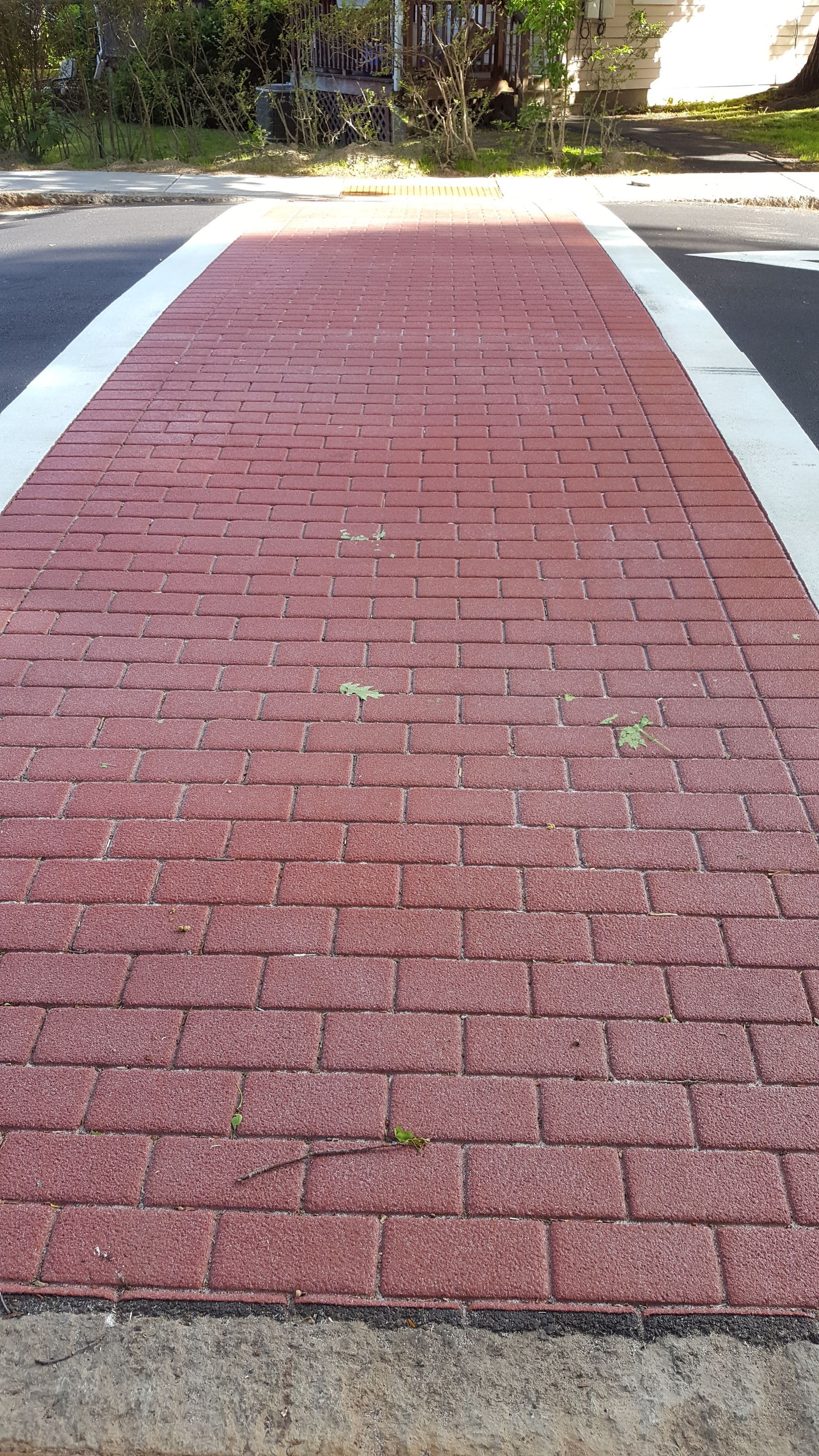 A red brick walkway with a white line on the side of the road.