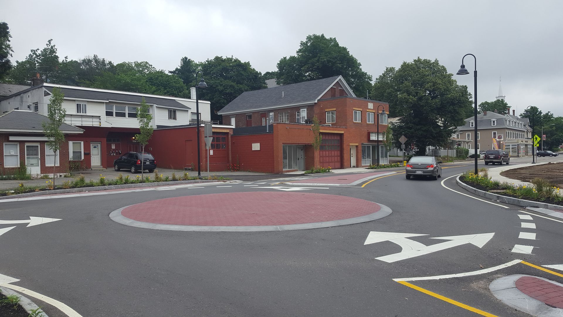 A car is driving through a roundabout in a small town.