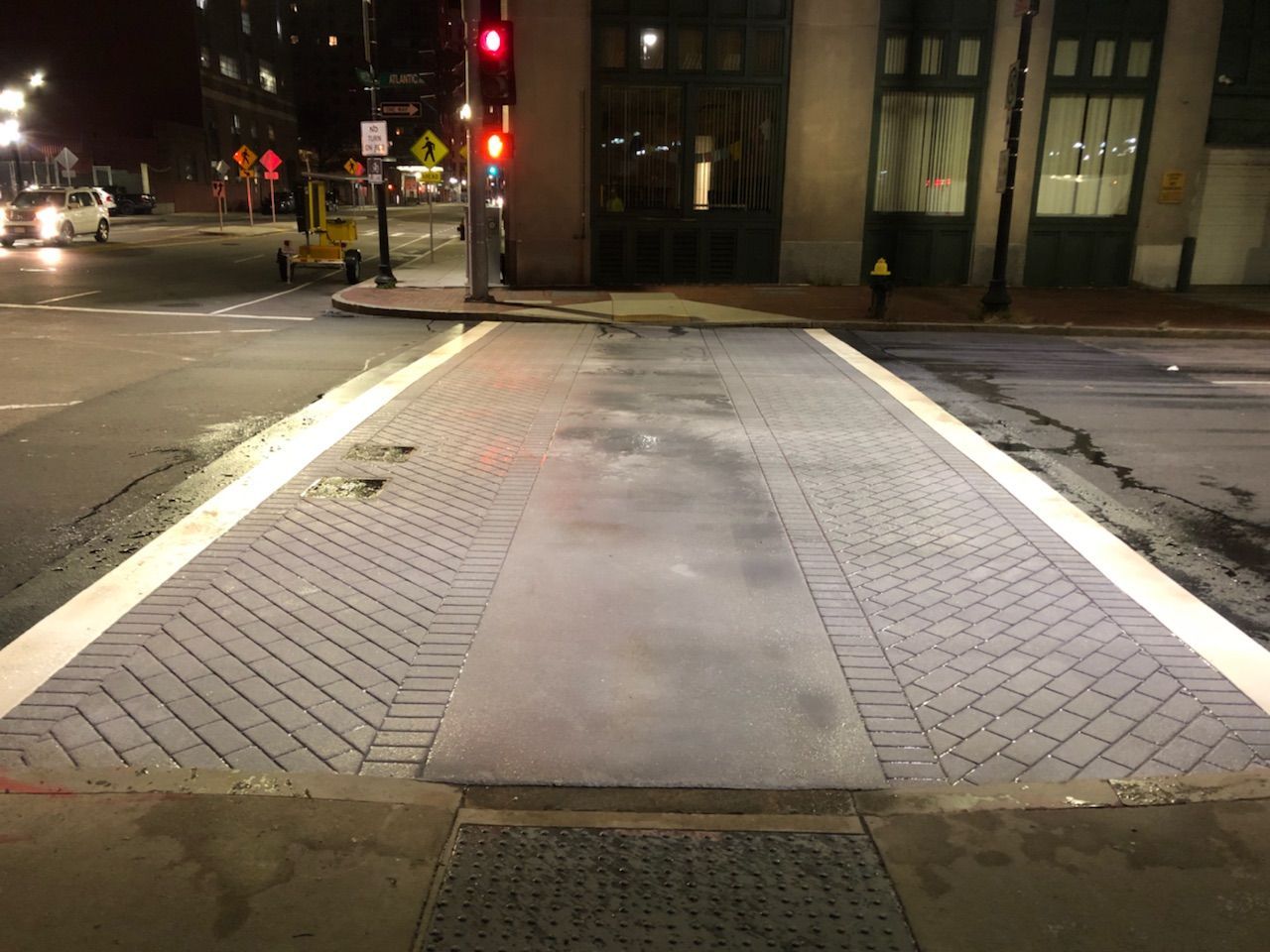 A crosswalk is lit up at night in front of a building