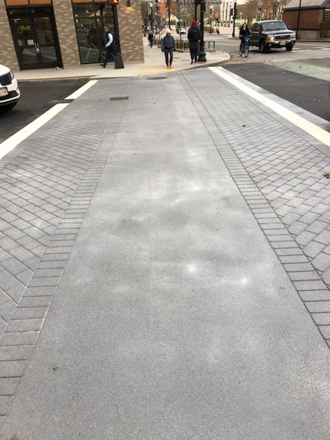 People are walking down a brick sidewalk in a city