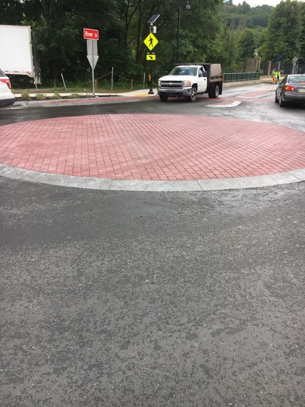 A truck is driving through a roundabout on a rainy day.