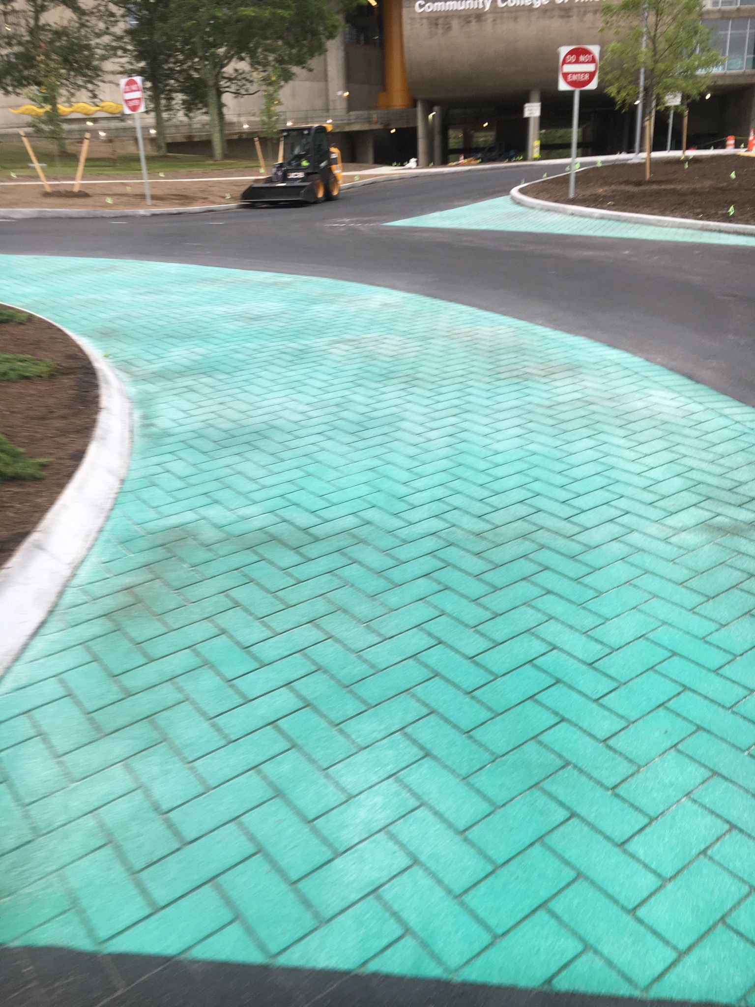 A tractor is driving down a green brick road.